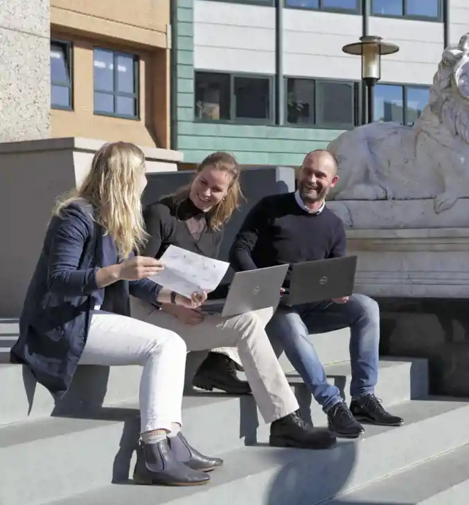 Sfeerimpressie van drie Collega's van Vindsubsidies die buiten werken op de trap met laptop