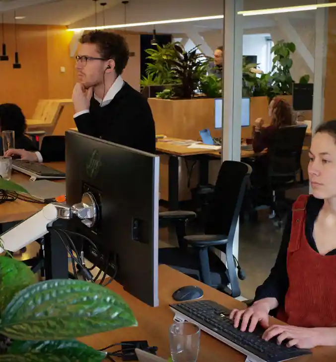 Collega's Djoeke en Mees werken achter de computer op het kantoor te maliebaan 16 in utrecht