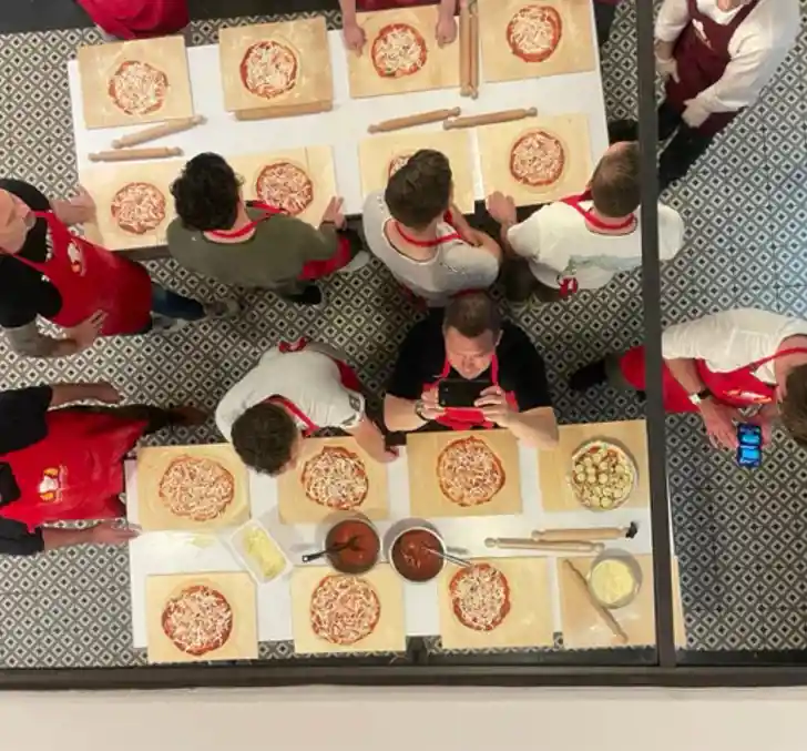 Bovenaanzicht van het team van N-abled die Pizza's aan het maken zijn, toont werkplezier