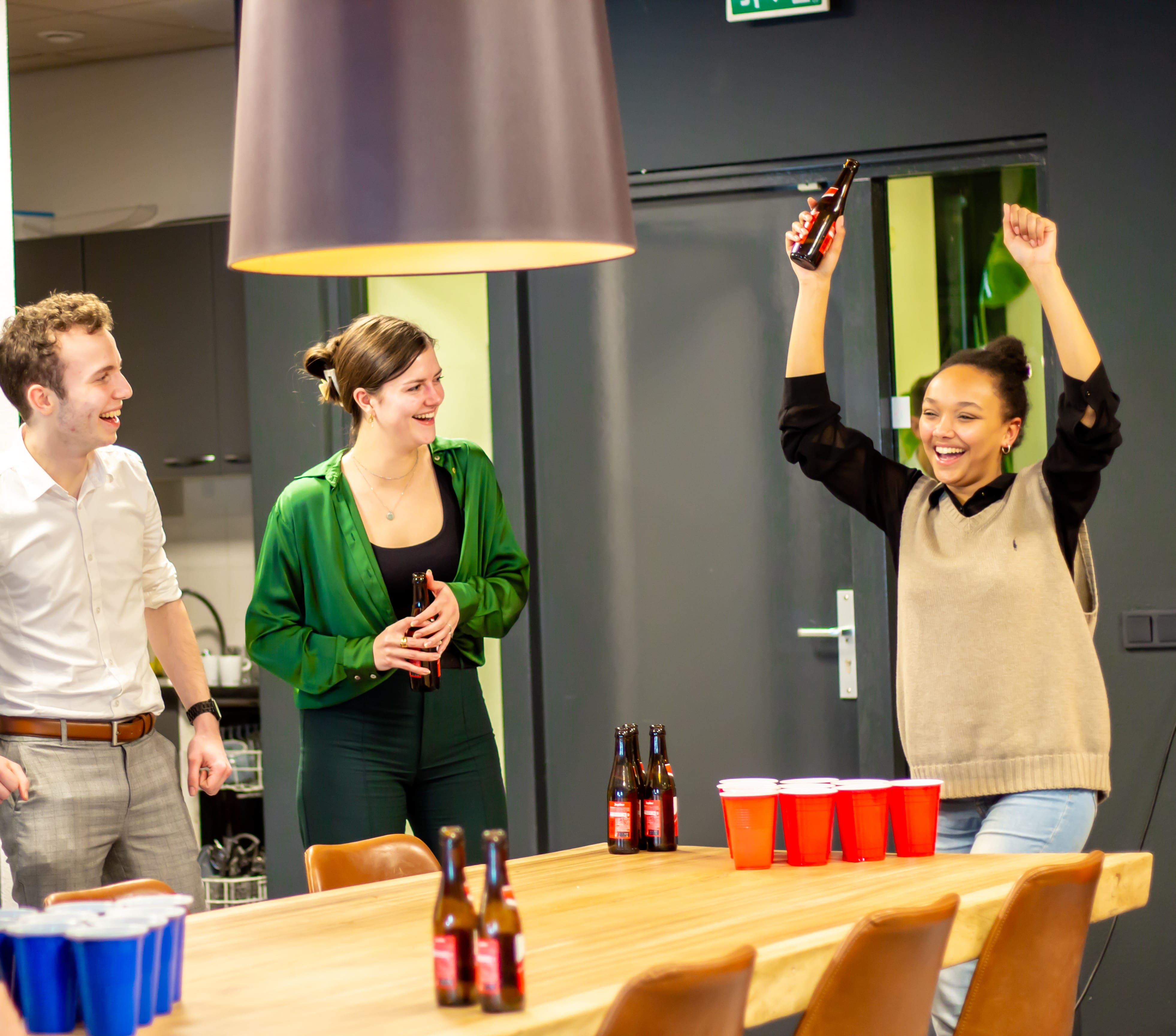 Drie Young Professionals van Young Consultant spelen bierpong en lachen